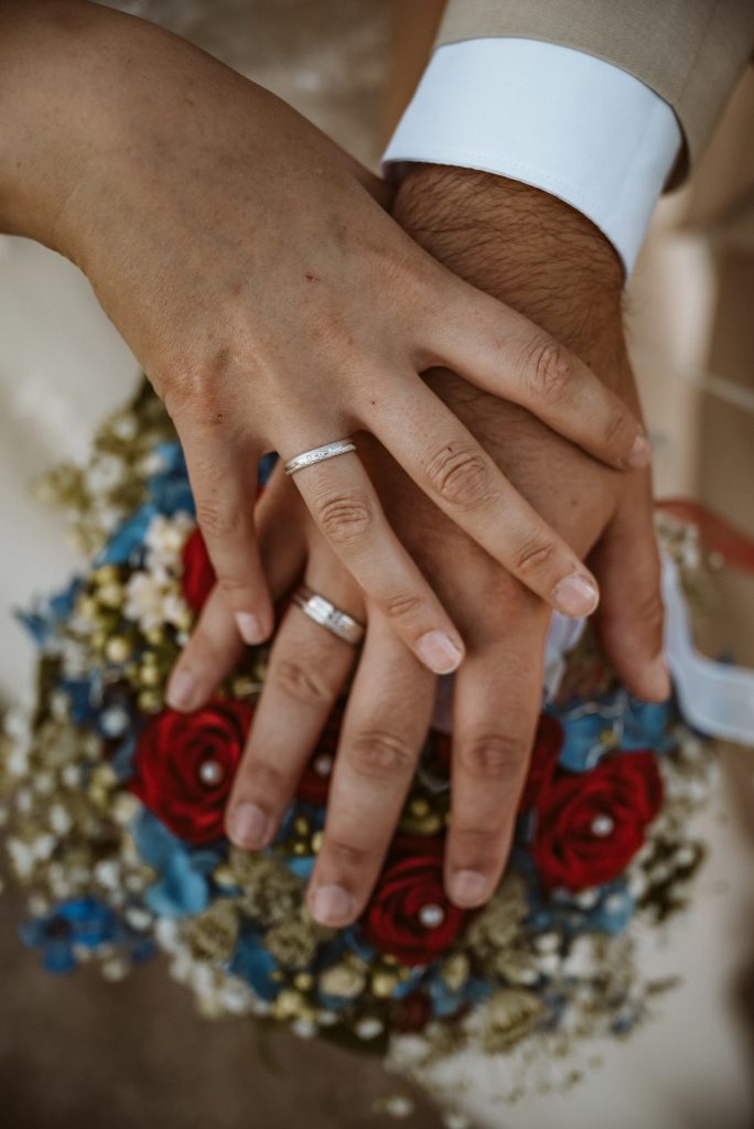 Hände über Blumenstraß mit Eheringen